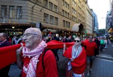 SYDNEY, AUSTRALIA - JUNE 08: Demonstrators carry a long piece of red fabric while marching along Market Street during a Pro-Palestine protest for Gaza on June 08, 2025 in Sydney, Australia. Organisers called on participants to wear the colour red to form a 'red line of humanity' while marching through the central business district (CBD). They are calling on the Australian Government to place sanctions on Israel. Picture: Lisa Maree Williams